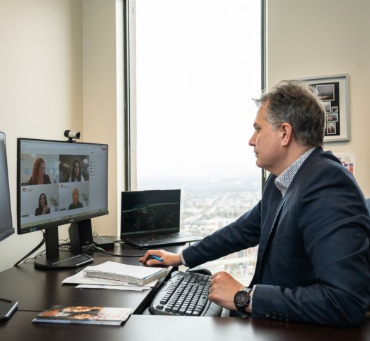 Gestionnaire assis devant son ordinateur tenant une réunion virtuelle avec son équipe en télétravail.