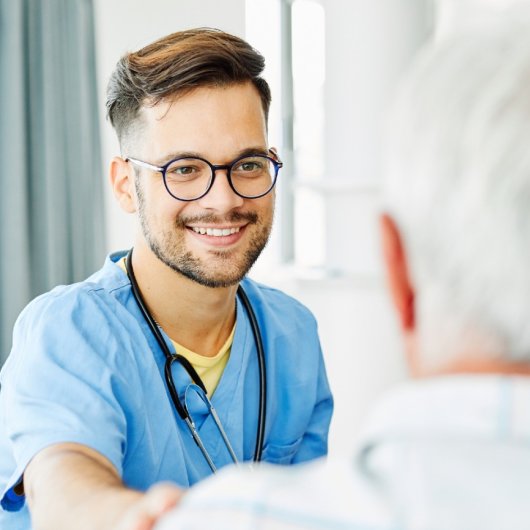 Un infirmier du réseau de la santé et des services sociaux sourit à une personne âgée.