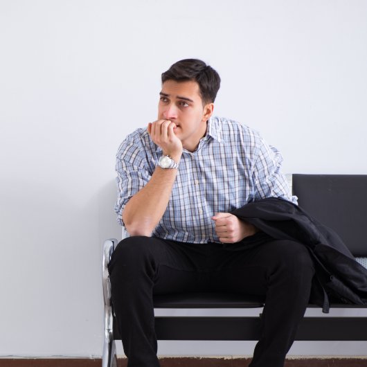 Un homme anxieux patiente assis sur une chaise d'une salle d'attente.